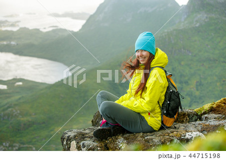 Image of happy tourist girl with backpack sitting on top of mountain in background of picturesque 44715198