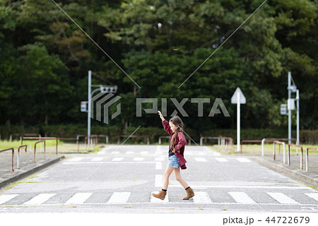 手を挙げて横断歩道を歩く女の子の写真素材