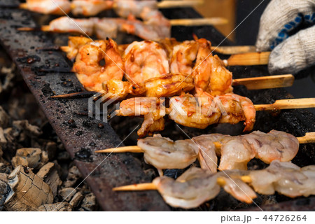 Grilled fried seafood on skewers on metal grid Grilled fried seafood on skewers on metal grid 44726264