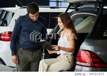Loving smart couple choosing a car at the car dealership showroom Loving smart couple choosing a car at the car dealership showroom 44727257