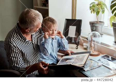 Grandfather and grandson on sofa at home. Grandpa and children watching old photos Grandfather and grandson on sofa at home. Grandpa and children watching old photos 44728042