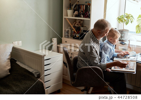 Grandfather and grandson on sofa at home. Grandpa and children watching old photos 44728508