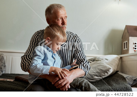 Grandfather and grandson using digital tablet while sitting on couch Grandfather and grandson using digital tablet while sitting on couch 44728522