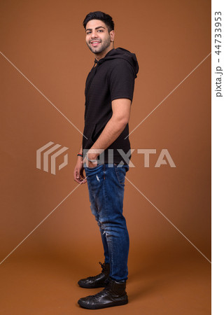 Young handsome Indian man against brown background 44733953