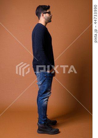 Young handsome Indian man against brown background 44733990