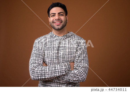 Young handsome Indian man against brown background Young handsome Indian man against brown background 44734011