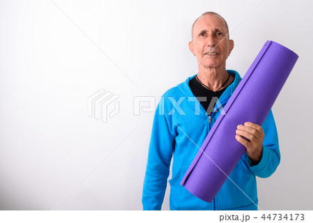 Studio shot of happy bald senior man smiling while holding yoga Studio shot of happy bald senior man smiling while holding yoga 44734173