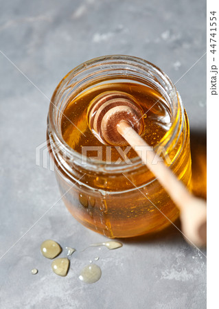 Wooden stick in a glass jar with fresh natural organic honey on a gray concrete table. Jewish New 44741554