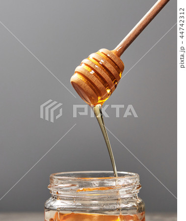 Dripping meadow organic natural honey from wooden dipper into a pot on a gray backgroun, pure raw Dripping meadow organic natural honey from wooden dipper into a pot on a gray backgroun, pure raw 44742312