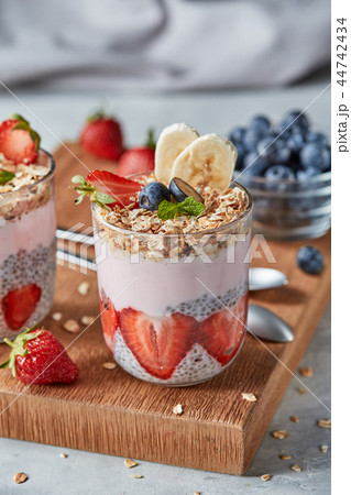 Dietary natural breakfast with fresh organic ingredients - berries, granola, banana in a glass on a Dietary natural breakfast with fresh organic ingredients - berries, granola, banana in a glass on a 44742434