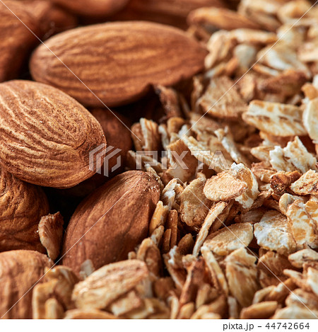 Uncooked oat flakes and almond nuts background. Close up, top view of organic natural product Uncooked oat flakes and almond nuts background. Close up, top view of organic natural product 44742664