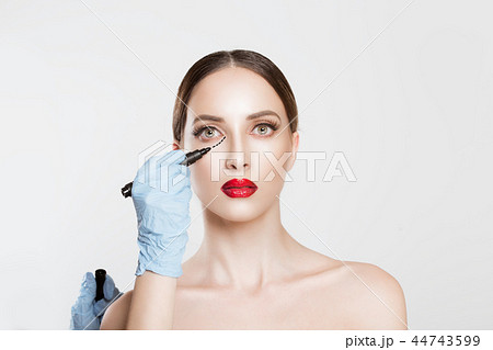Doctor Hands drawing marks on female face 44743599