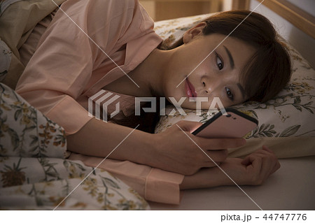 ベッドでスマホを見る若い女性 ベッドでスマホを見る若い女性 44747776