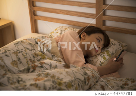 ベッドでスマホを見る若い女性 44747781