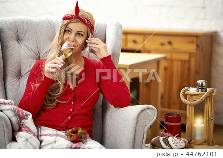 young beautiful woman in an armchair with prosecco wrapped in a blanket during Christmas time young beautiful woman in an armchair with prosecco wrapped in a blanket during Christmas time 44762101