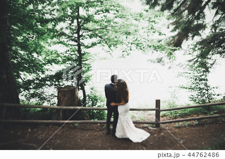 Newly married couple running and jumping in park while holding hands Newly married couple running and jumping in park while holding hands 44762486