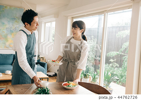 食事をテーブルに運ぶ若い夫婦 日本人男女 44762726