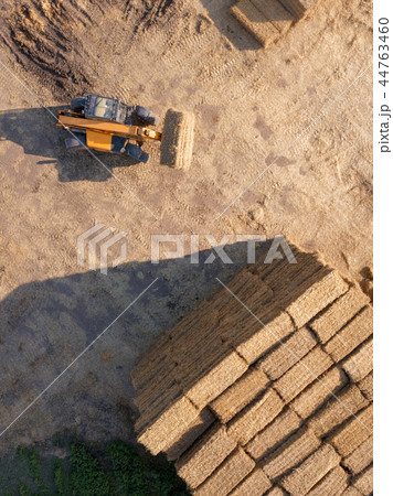 Aerial view from drone agricultural machine collecting bales of hay on a field. Farm industry. Top 44763460