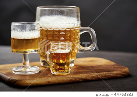 three golden delicious beers on an old black wooden table 44763832