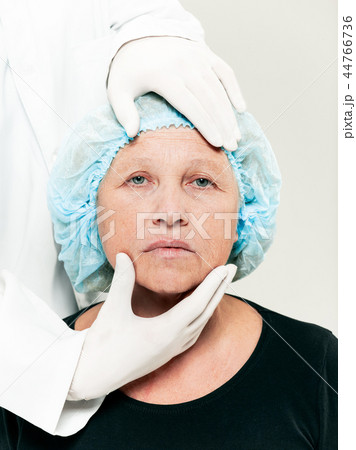 surgeon doing skin check on mid age woman before plastic surgery surgeon doing skin check on mid age woman before plastic surgery 44766736