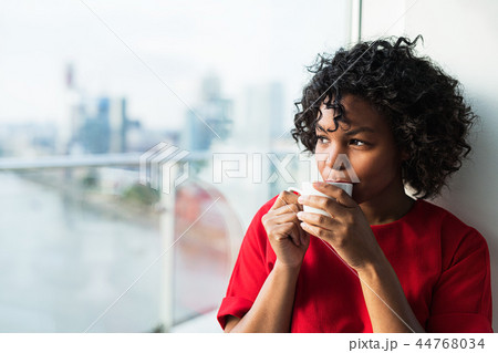 A close-up of a woman standing by the window drinking coffee. A close-up of a woman standing by the window drinking coffee. 44768034