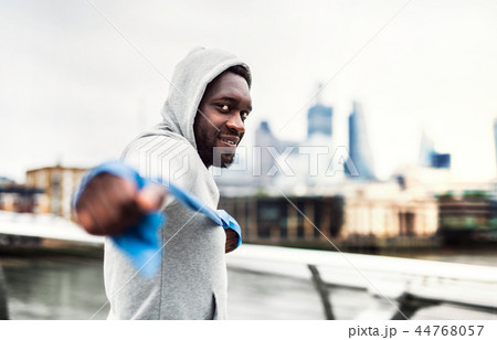 Young black sportsman exercising with elastic rubber bands in London. 44768057
