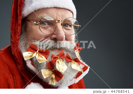Joyful Santa Claus with cute bows in beard standing on gray background 44768541