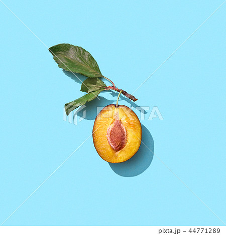Half a ripe plum with green leaves on a blue background with copy space. Vitamin food. Flat lay 44771289