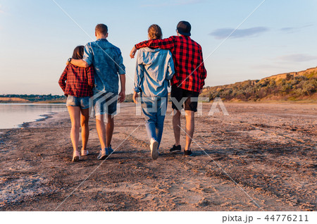 friends on beach together walking during sunset 44776211