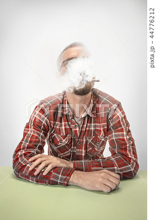 Handsome hipster man smoking cigarette at home. Man looking upwards and enjoying spending free time. 44776212