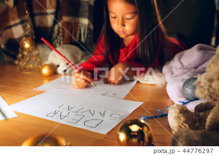Merry Christmas and Happy Holidays. Cute little child girl writes the letter to Santa Claus near 44776297
