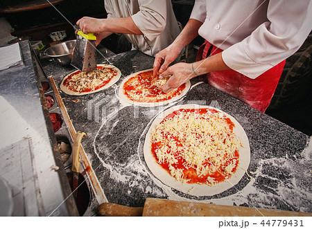 Preparation of three pizzas. Cheese on a dough with tomato paste 44779431