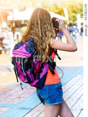 Tourist girl with backpack taking pictures on digital camera Tourist girl with backpack taking pictures on digital camera 44780149