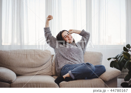 Young woman relaxing on a couch in living room Young woman relaxing on a couch in living room 44780167