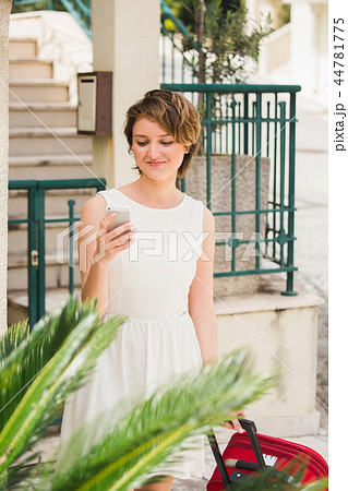 Young woman travelerwith a red suitcase and phone  44781775