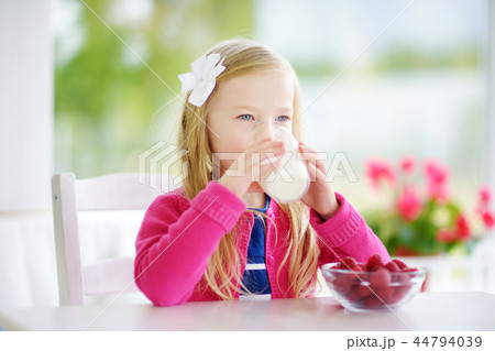 Pretty little girl eating raspberries with milk Pretty little girl eating raspberries with milk 44794039
