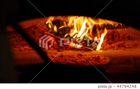 Pizza in the oven. A good fire burns in the oven. 44794248
