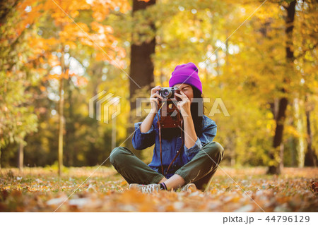 girl in hat with professional camera on fall season park 44796129