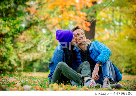 Young couple sitting on ground in a autumn season time park  44796206