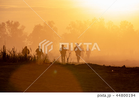 silhouette action soldiers walking hold weapons the background is smoke and sunset. War, military 44800194
