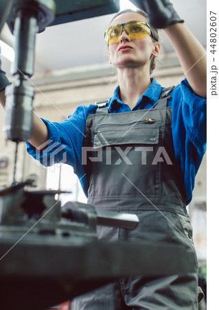 Woman worker in metal workshop using pedestal drill 44802607