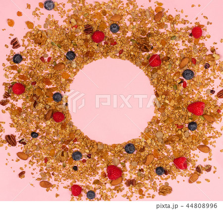Scattered granola, nuts and berries on pink background. Scattered granola, nuts and berries on pink background. 44808996