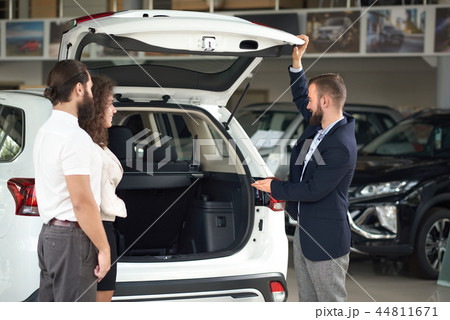 Manager of car center showing to couple cargo space. Manager of car center showing to couple cargo space. 44811671