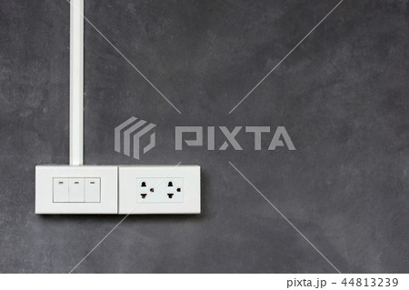 light switch and outlet plug on concrete wall 44813239