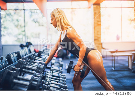Tanned athletic fitness woman doing exercises for back and posing in the gym Tanned athletic fitness woman doing exercises for back and posing in the gym 44813300