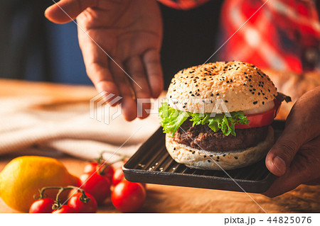 Man hand holding delicious homemade hamburger Man hand holding delicious homemade hamburger 44825076