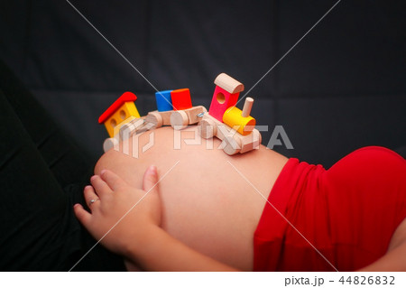 Kids wooden train toy on a pregnant belly.  44826832