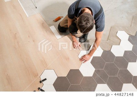 Male worker installing new wooden laminate flooring. The combination of wood panels of laminate and Male worker installing new wooden laminate flooring. The combination of wood panels of laminate and 44827148