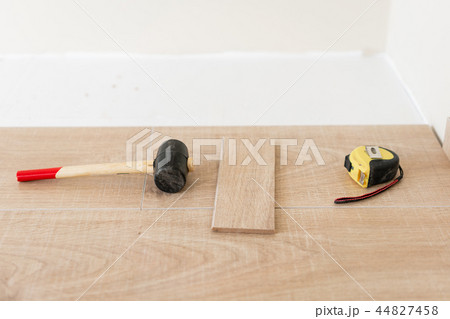 Installing laminate parquet in interior. On the floor lie different carpenter tools. Hammer and Installing laminate parquet in interior. On the floor lie different carpenter tools. Hammer and 44827458