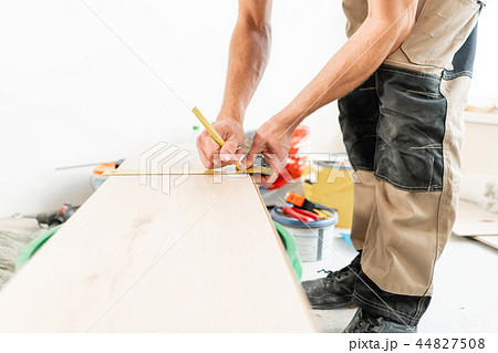 Male worker applies markings to the Board for cutting with a electrofret saw. installing new wooden 44827508